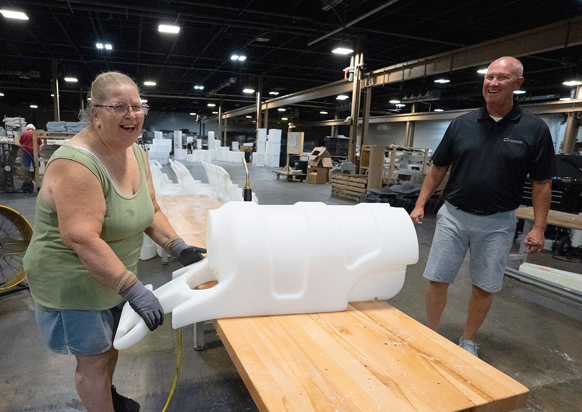 employee finishing a molded part laughing with Todd